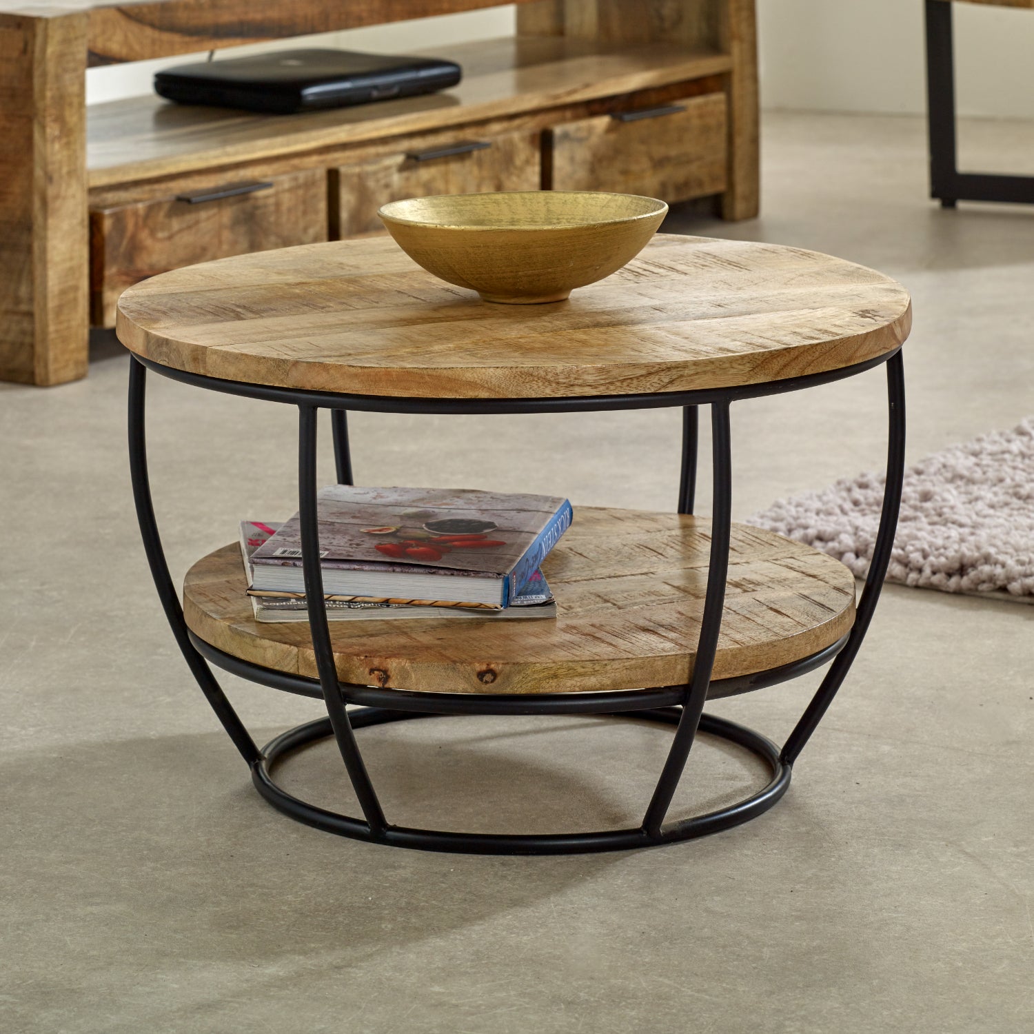 Merlin Mango Wooden & Metal Coffee Table With Shelf Round wooden coffee table with metal frame in a room setting