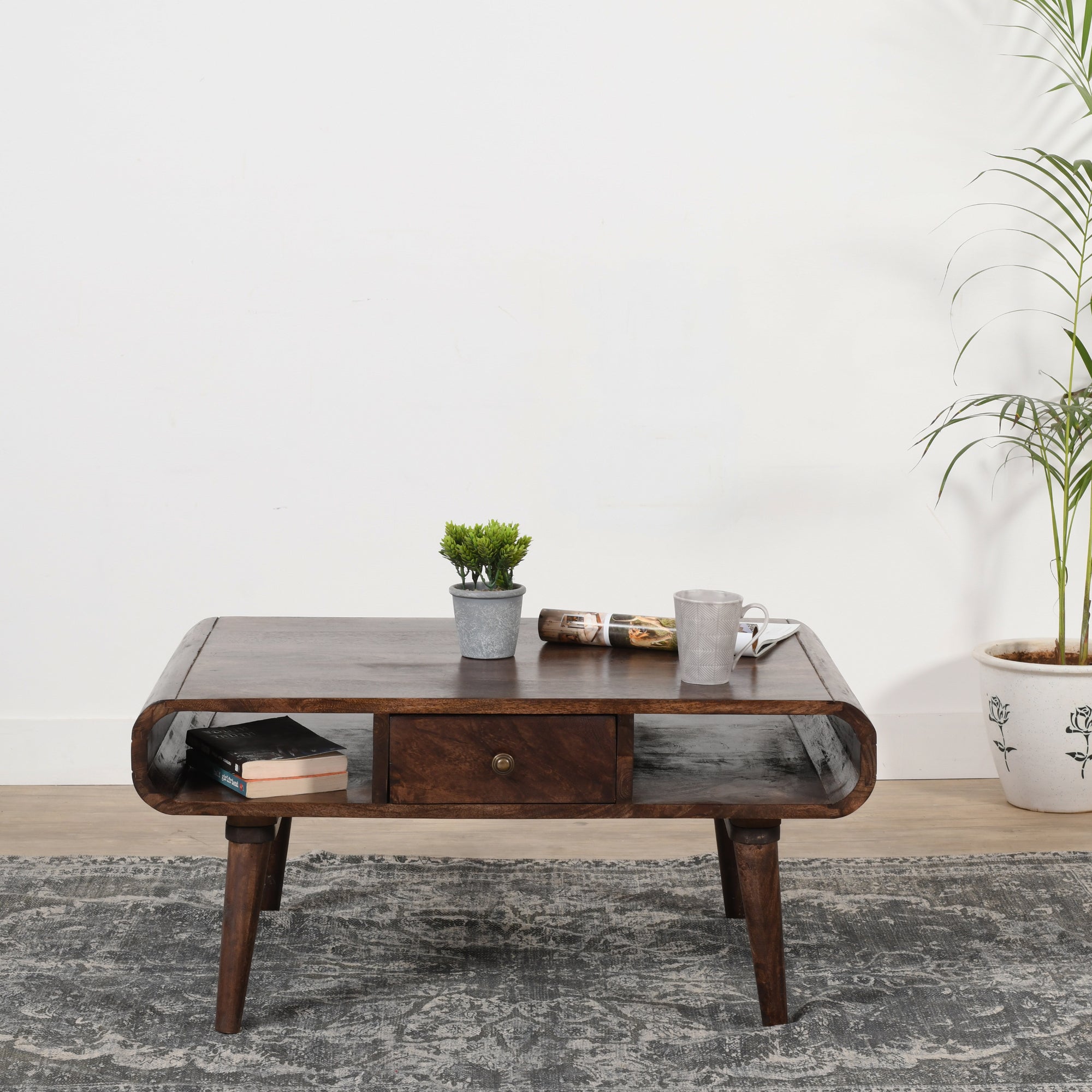 Franklin Dark Mango Wood Coffee Table with Drawer Wooden coffee table with decorative items on a gray rug