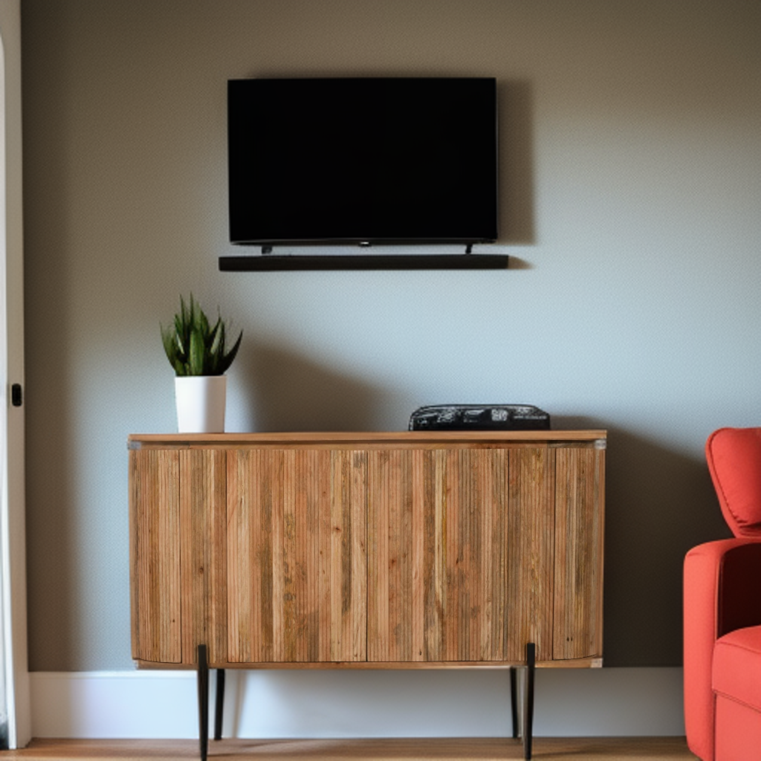 Wooden entertainment console with TV above, plant on top, and red chair to the side.
